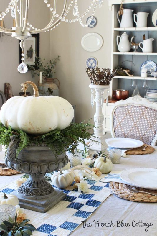 large urn with a white pumpkin on a bed of ferns