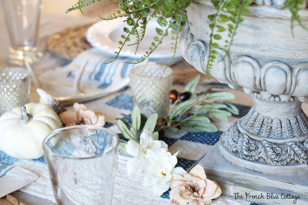 neutral fall tablescape with a blue and white quilt and mercury hobnail votives