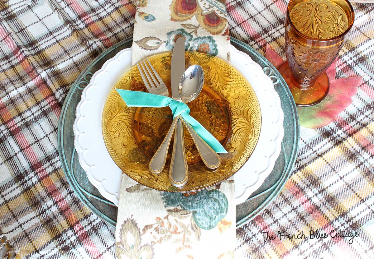 Fall place setting with amber glassware, velvet ribbon, and a verdigris charger.