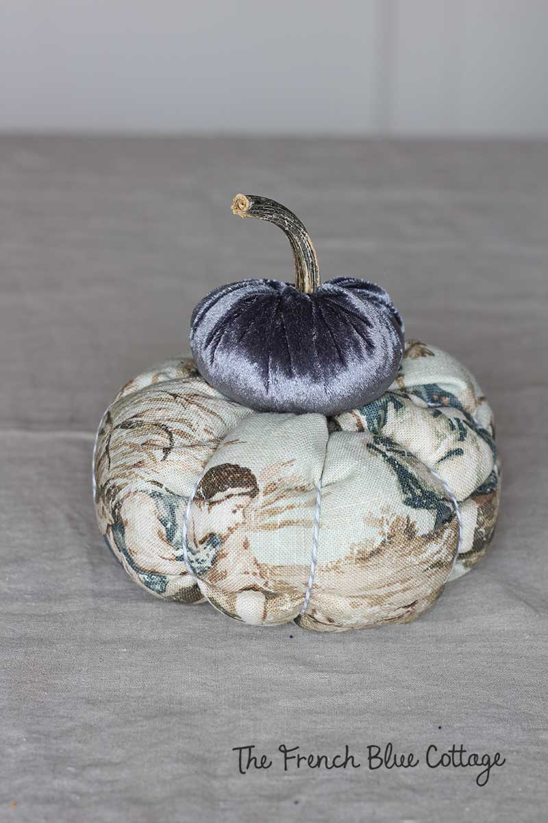 A velvet pumpkin stacked on top of a toile pumpkin.