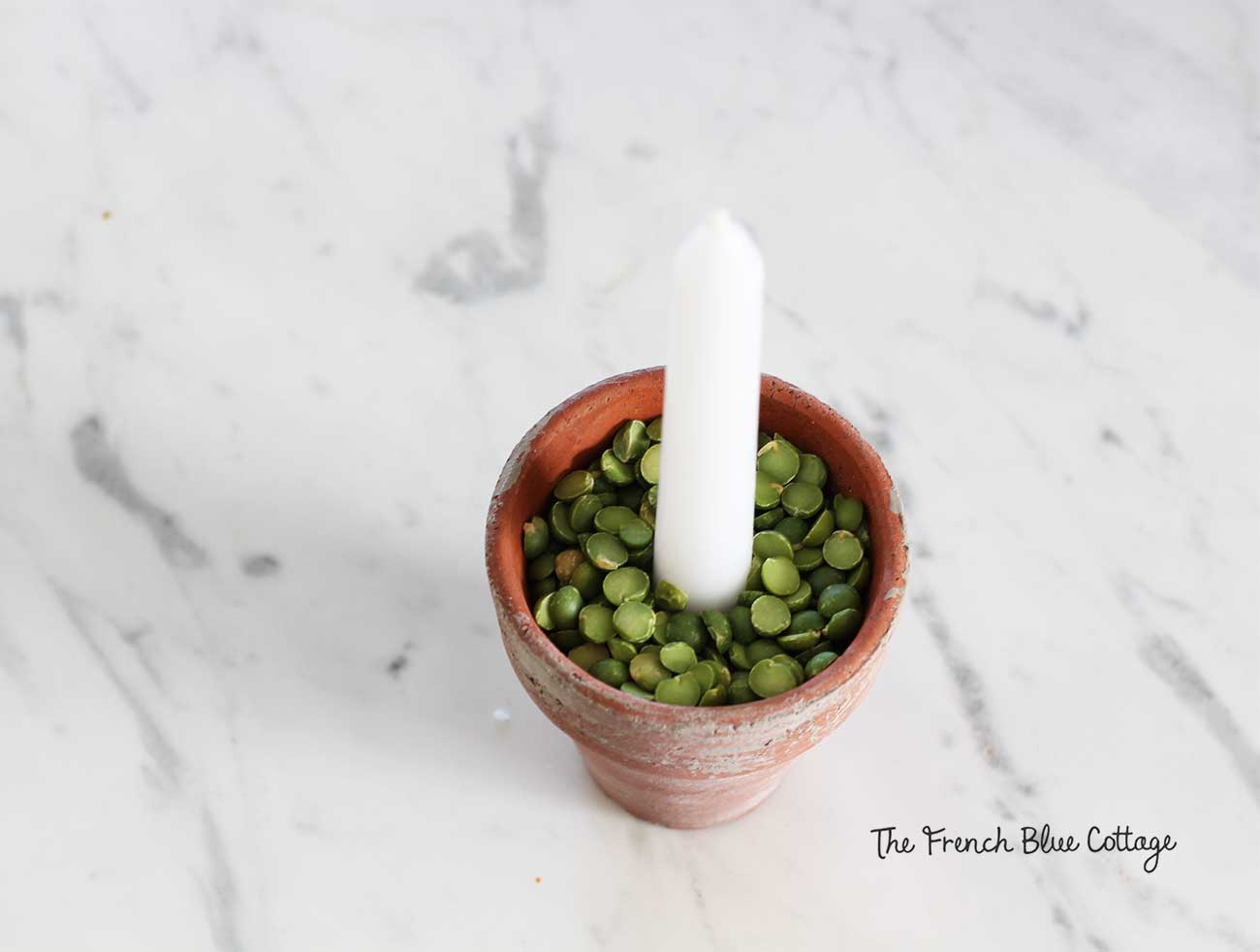 Dried split peas look festive and hold the candle in place.