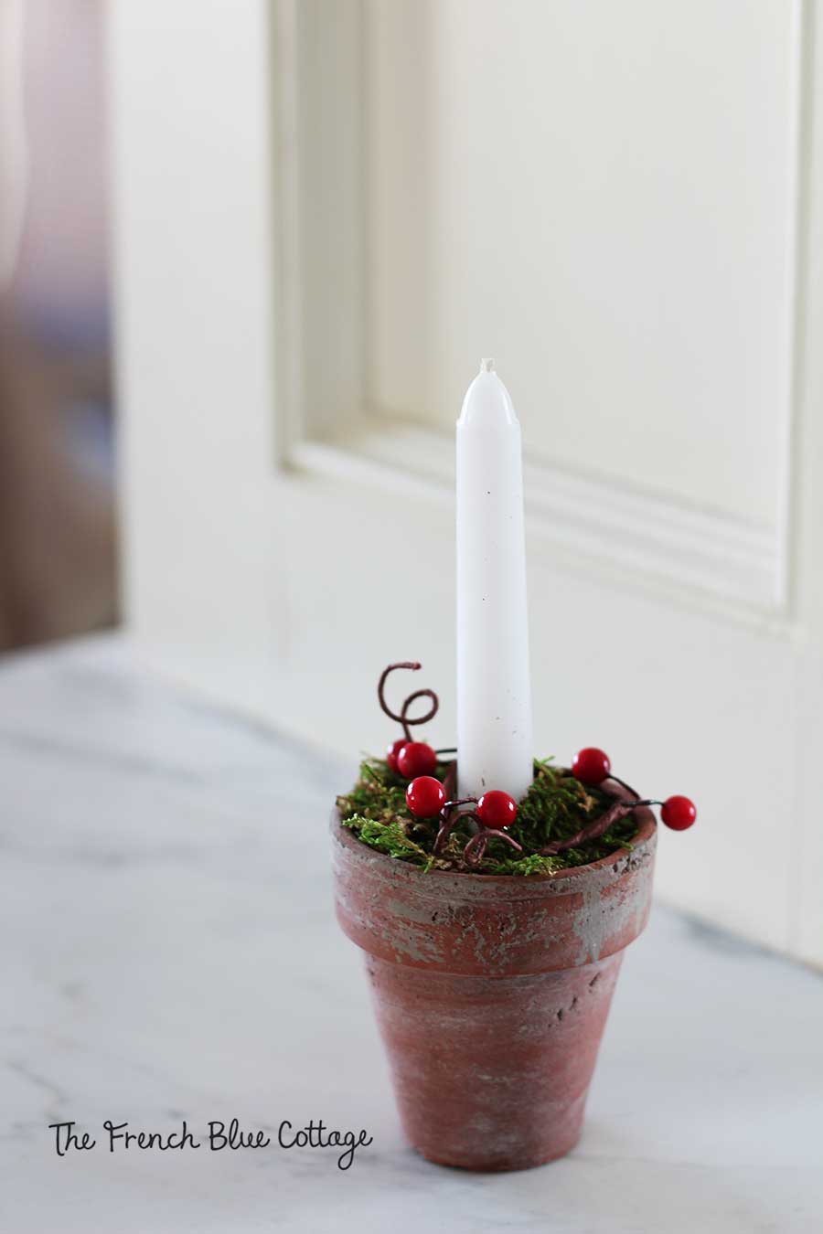 Faux red berries on a Christmas candle.