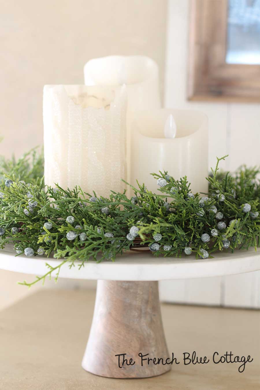 Candles on a cake stand with winter wreath.