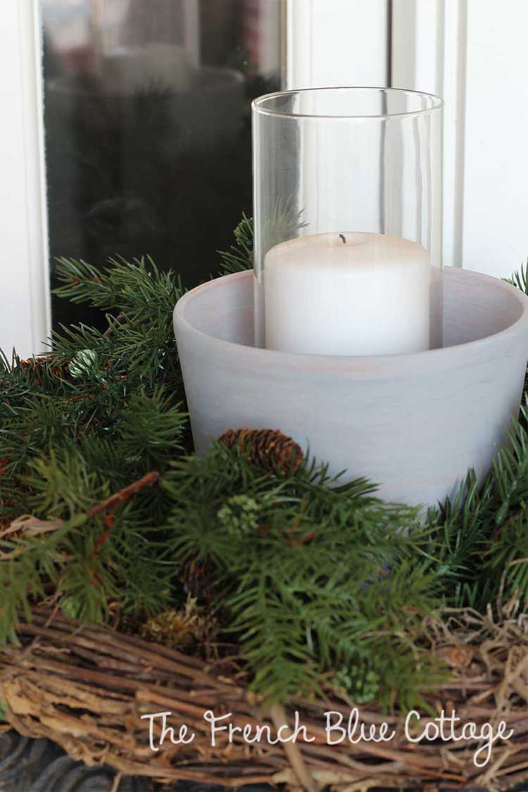 Whitewashed clay pots with candles and greenery on front porch.