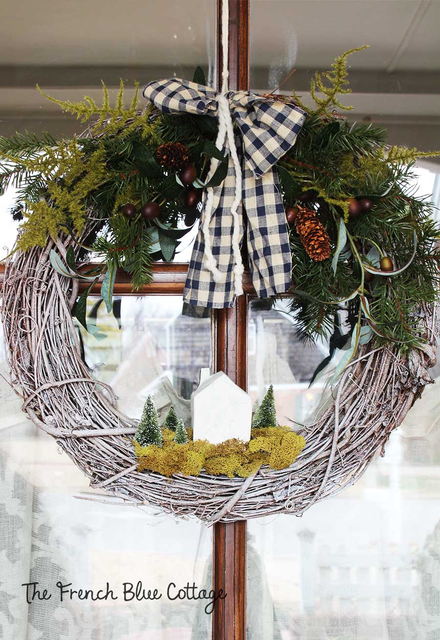 Winter greenery wreath with house and trees.