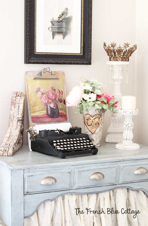 Vignette with typewriter, candle, flowers, and a painting.