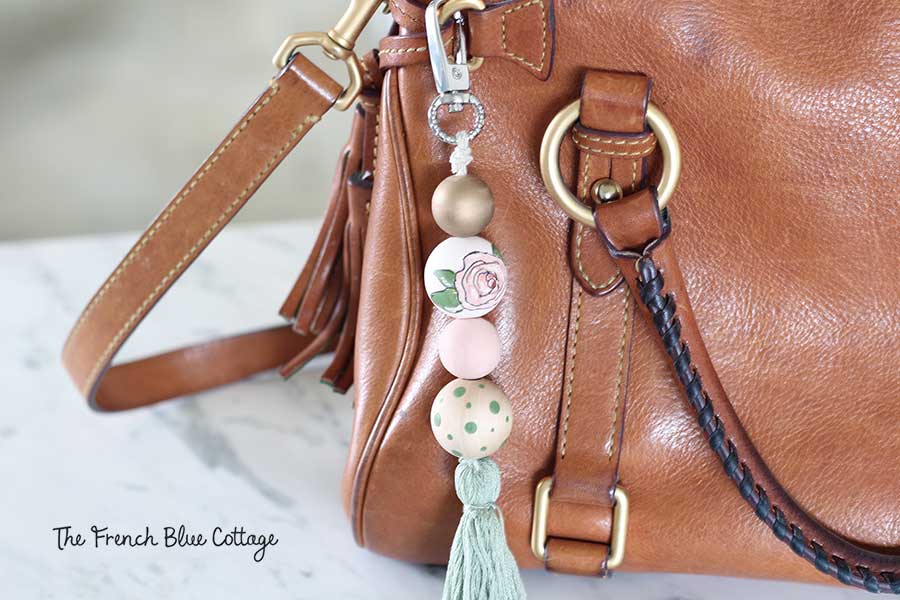 A DIY hand-painted floral wood bead and tassel purse clip or keychain.