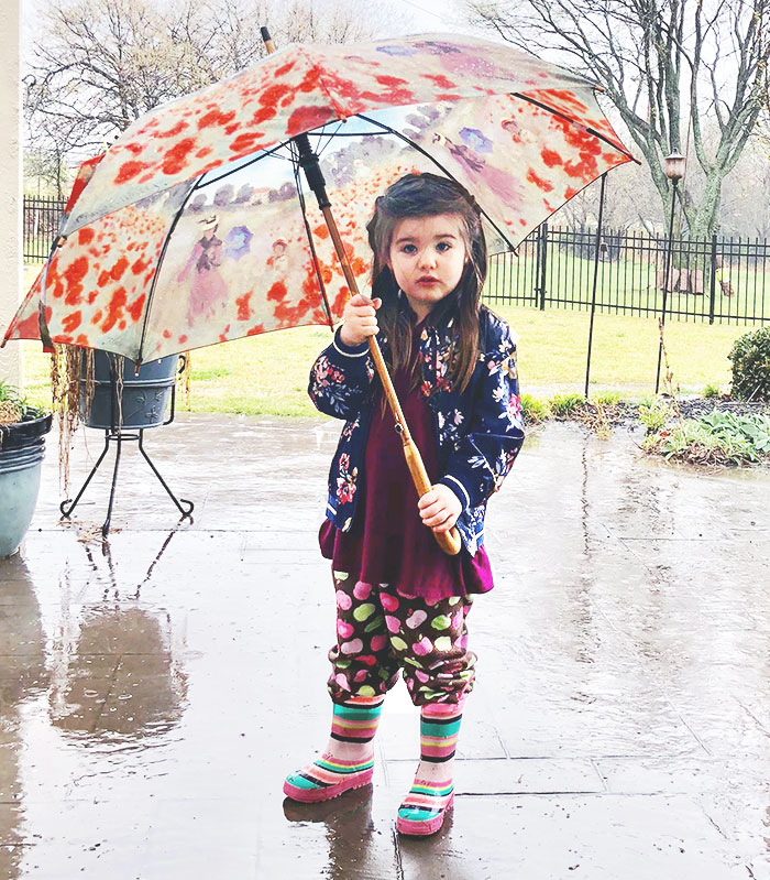 A little girl with an umbrella in the rain.
