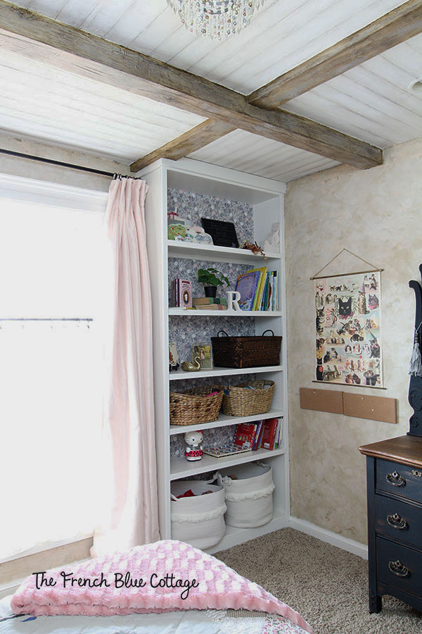 little girl's bookshelf with starched fabric wallpaper back