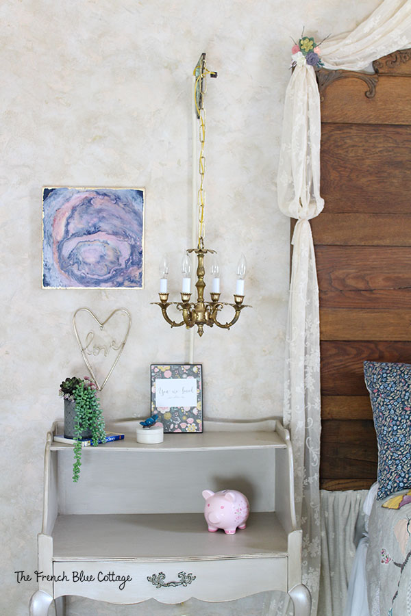 Chandelier and night stand in French country bedroom