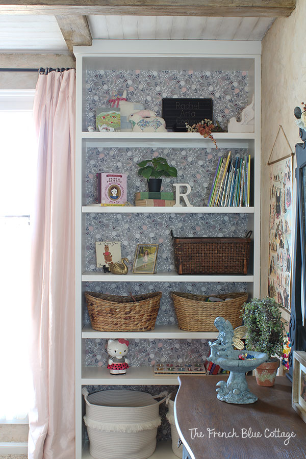 little girl's bookshelf with starched fabric wallpaper