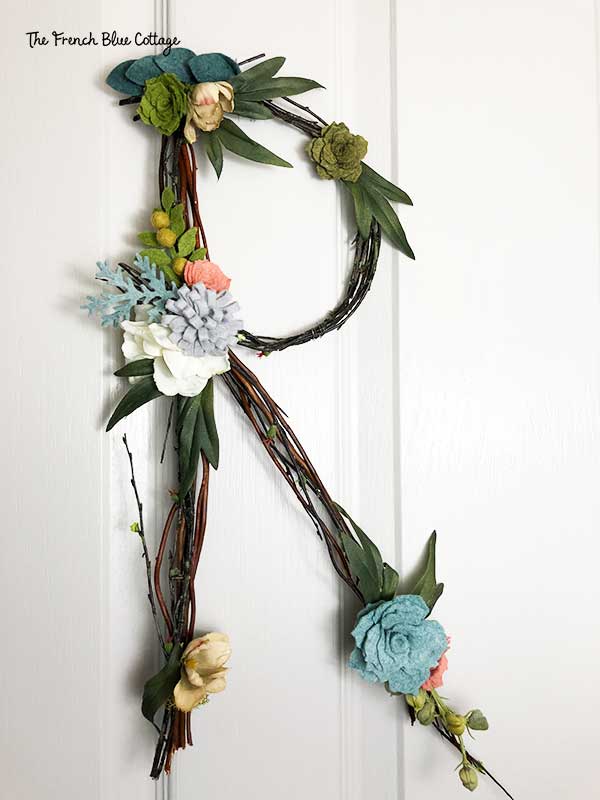 twig letter initial with felt flowers hanging on door