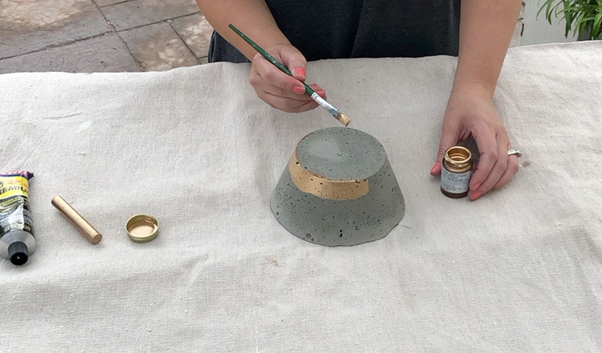 painting a concrete bowl with gold gilding liquid