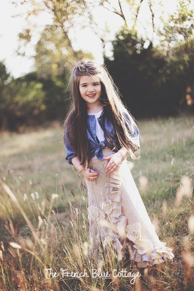 Little girl standing in a field in a long linen skirt