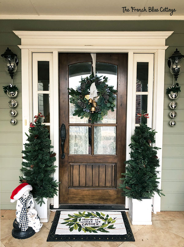 arched front door with christmas trees and wreath