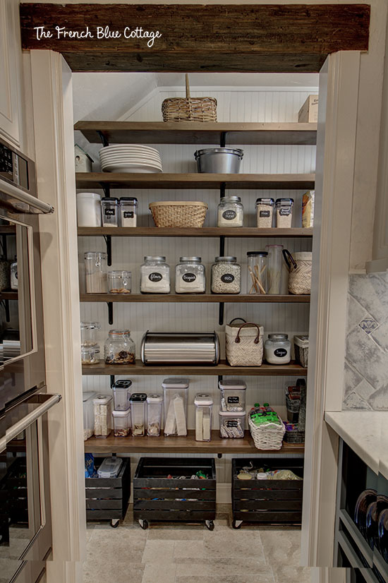 pantry under stairs with open shelves and beadboard