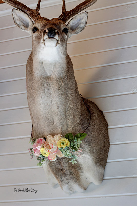 deer head on wall with flowers around neck