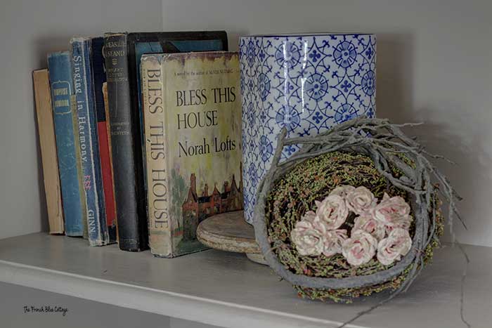aged silk flowers in a bird's nest on a bookshelf