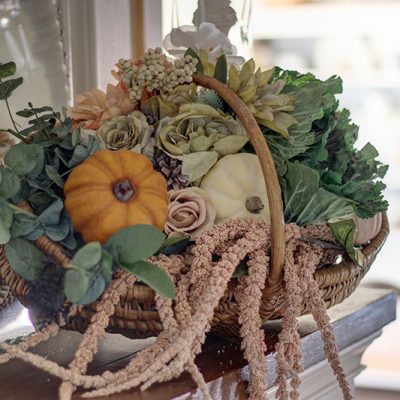 large basket of flowers and pumpkins on a fall mantel