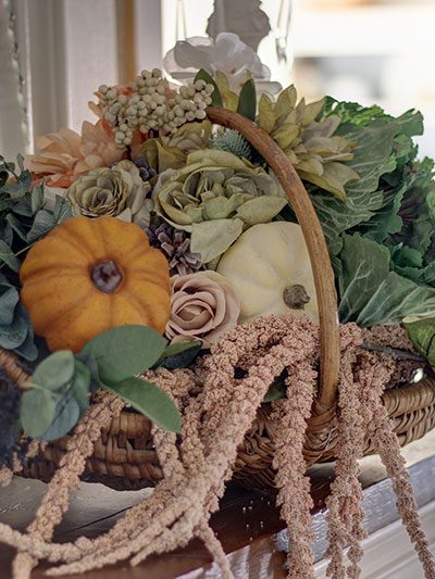 large basket of flowers and pumpkins on a fall mantel