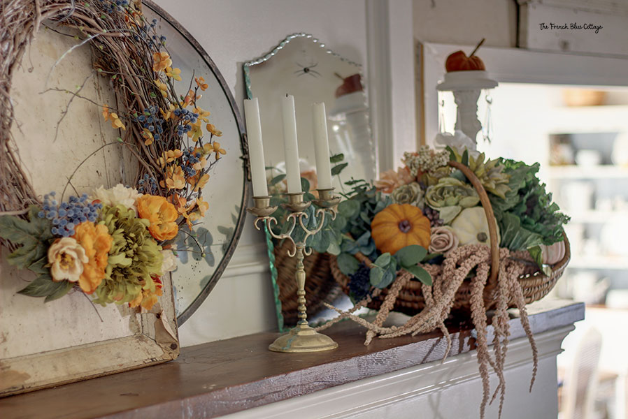 white mantel with fall decor including a basket of flowers, pumpkins, and a wreath
